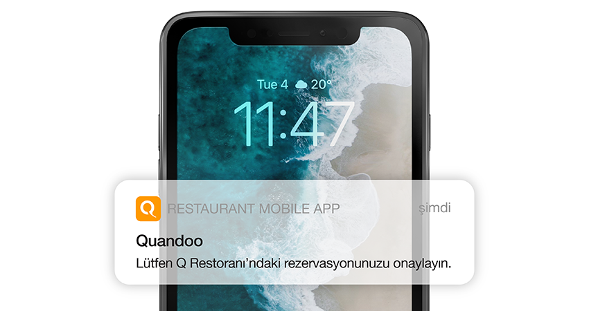 “Lütfen Q Restoranı’ndaki rezervasyonunuzu onaylayın.” ifadesinin yer aldığı Quandoo uygulama bildirimi görüntülenen bir akıllı telefon