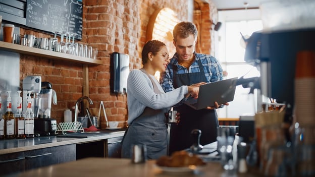 Two people using a laptop-based restaurant technology tool.